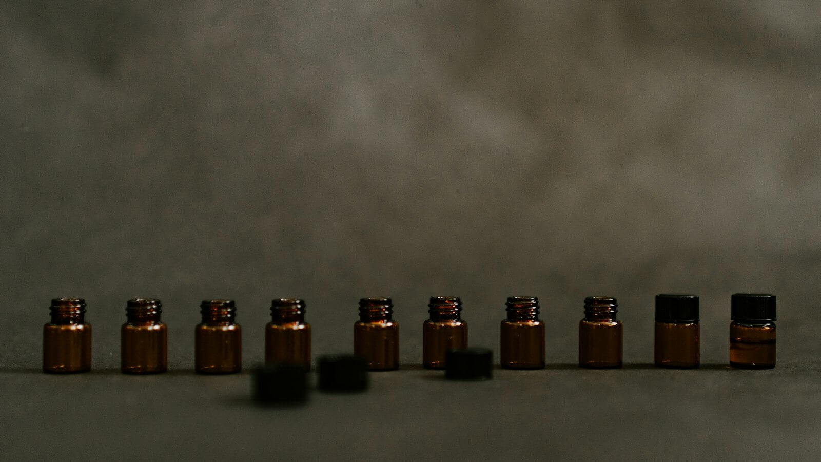 Row of small amber glass bottles on a dark surface