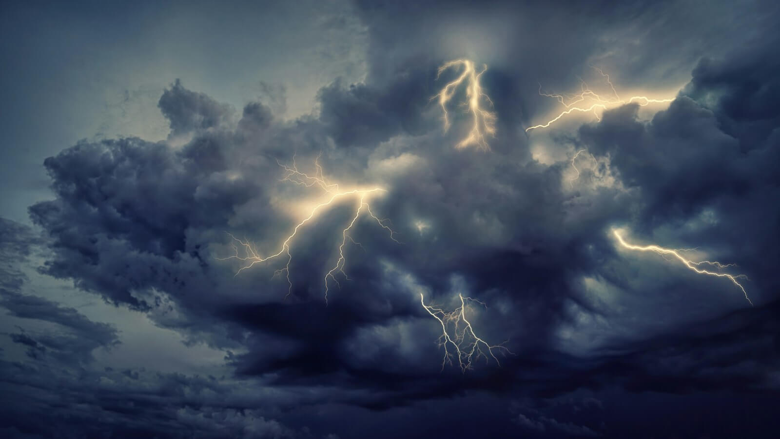 Lightning streaks across dark storm clouds at night