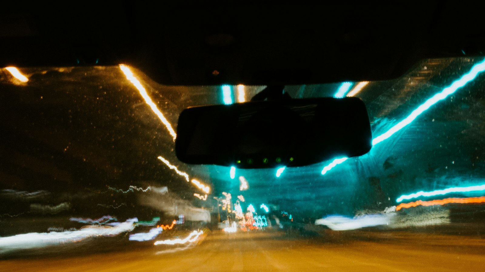 Streaks of headlights and street lights seen through a car windshield at night